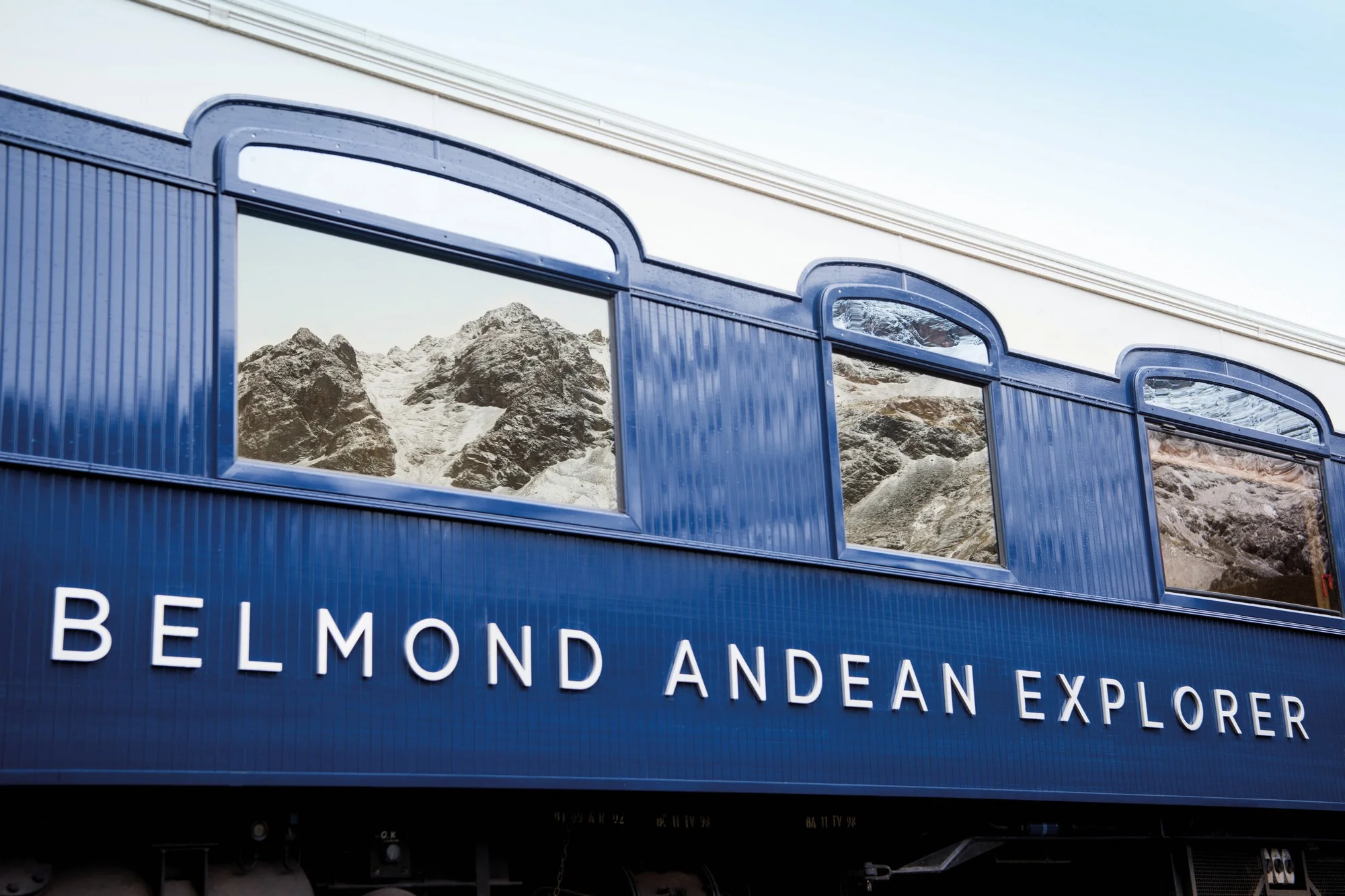 Logo Andean Explorer sur les fen&ecirc;tres avec reflets des montagnes andines &mdash; identit&eacute; visuelle du train Belmond au P&eacute;rou
