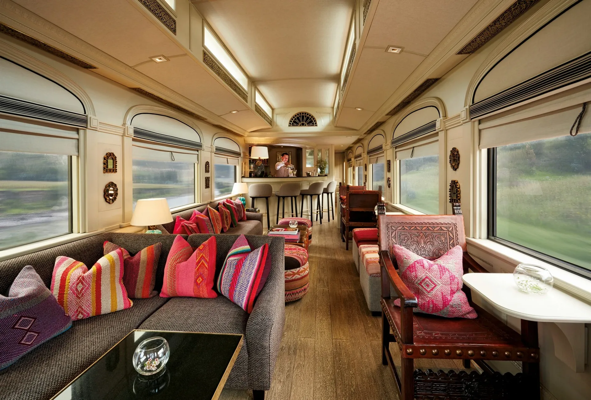 Salon lounge de l'Andean Explorer avec coussins tiss&eacute;s p&eacute;ruviens et larges fen&ecirc;tres sur les Andes