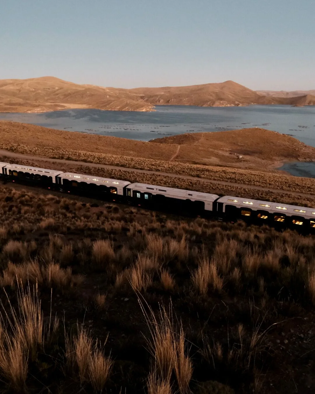 L'Andean Explorer baign&eacute; d'une lumi&egrave;re dor&eacute;e &agrave; la nuit tombante sur le lac Titicaca