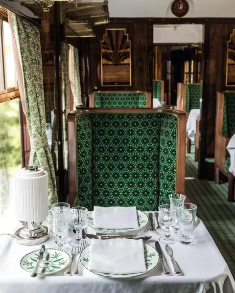 Table dress&eacute;e dans le wagon Cygnus &mdash; vaisselle verte, cristal, nappes blanches