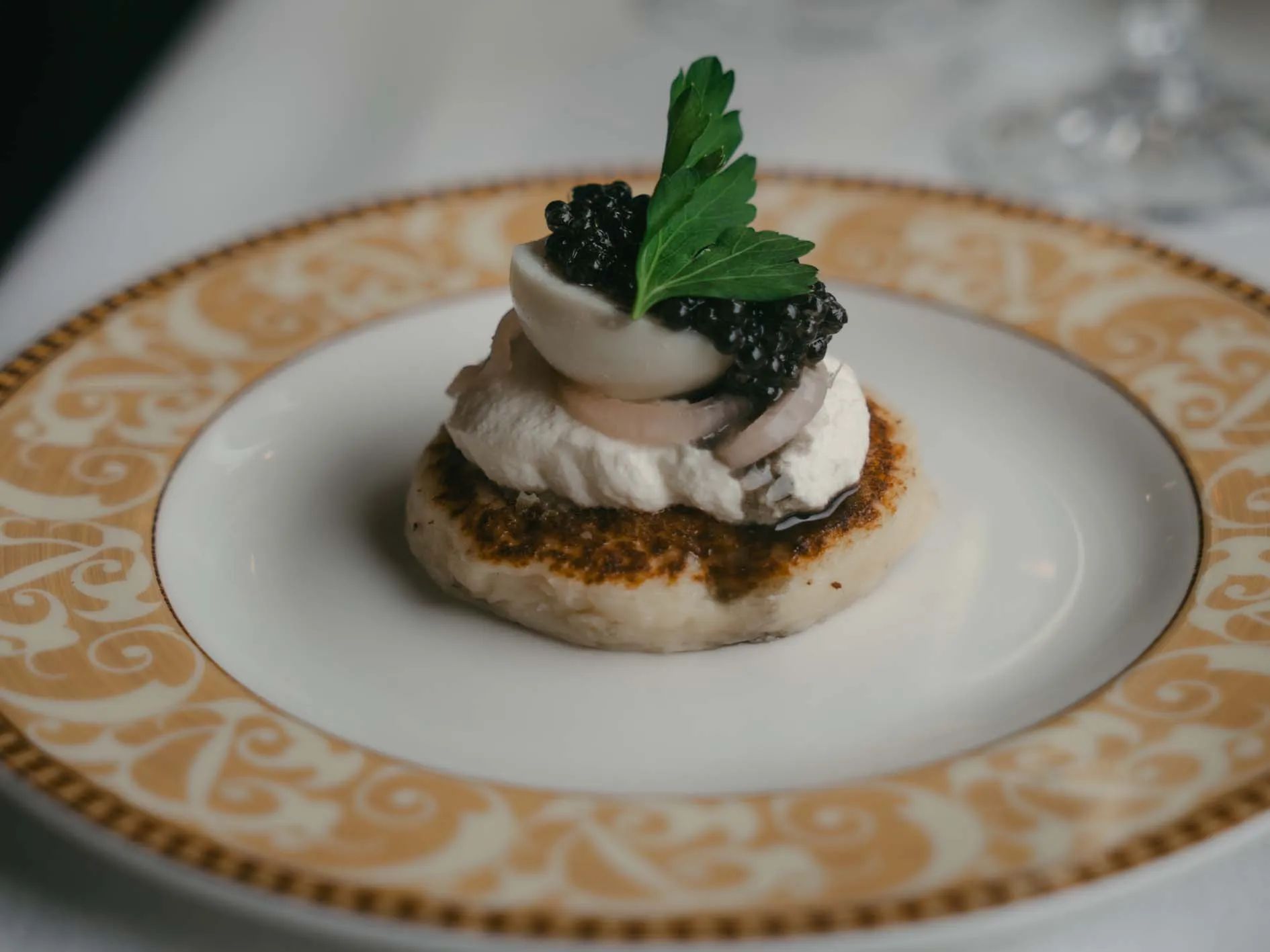 Entr&eacute;e gastronomique Northern Belle : blini, cr&egrave;me et caviar sur assiette or