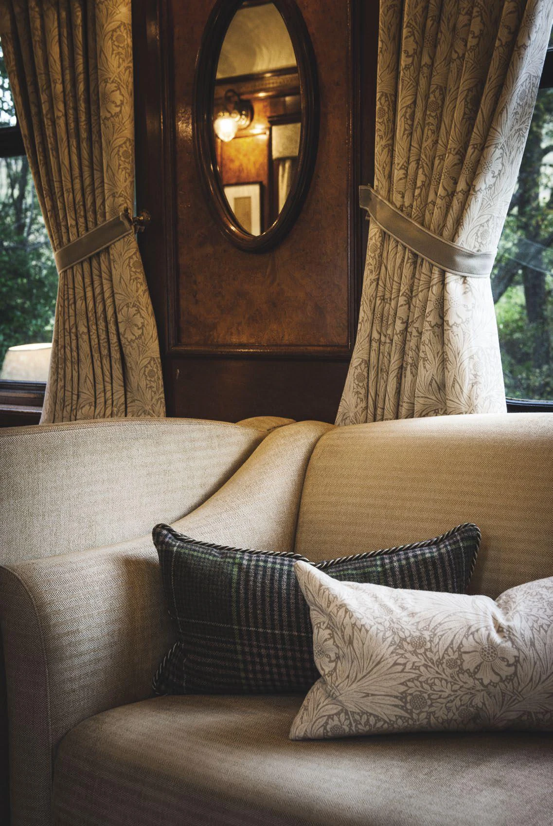 Salon de la State Cabin du Royal Scotsman avec canap&eacute; en tweed, coussins tartan et miroir ovale
